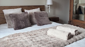 A neatly made bed with a fluffy blanket and pillows, a bedside lamp, and a wooden nightstand. - New apartment "La vieille maison", near Serre Chevalier (Villar-Saint-Pancrace)