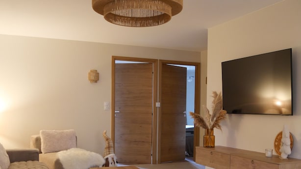 A modern living room with a large TV, a wooden cabinet, and a unique woven light fixture. - New apartment "La vieille maison", near Serre Chevalier (Villar-Saint-Pancrace)