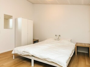 A minimalist bedroom with a single bed, a wardrobe, and a bedside table. - 5 Star Holiday Home in Saltum (Saltum)