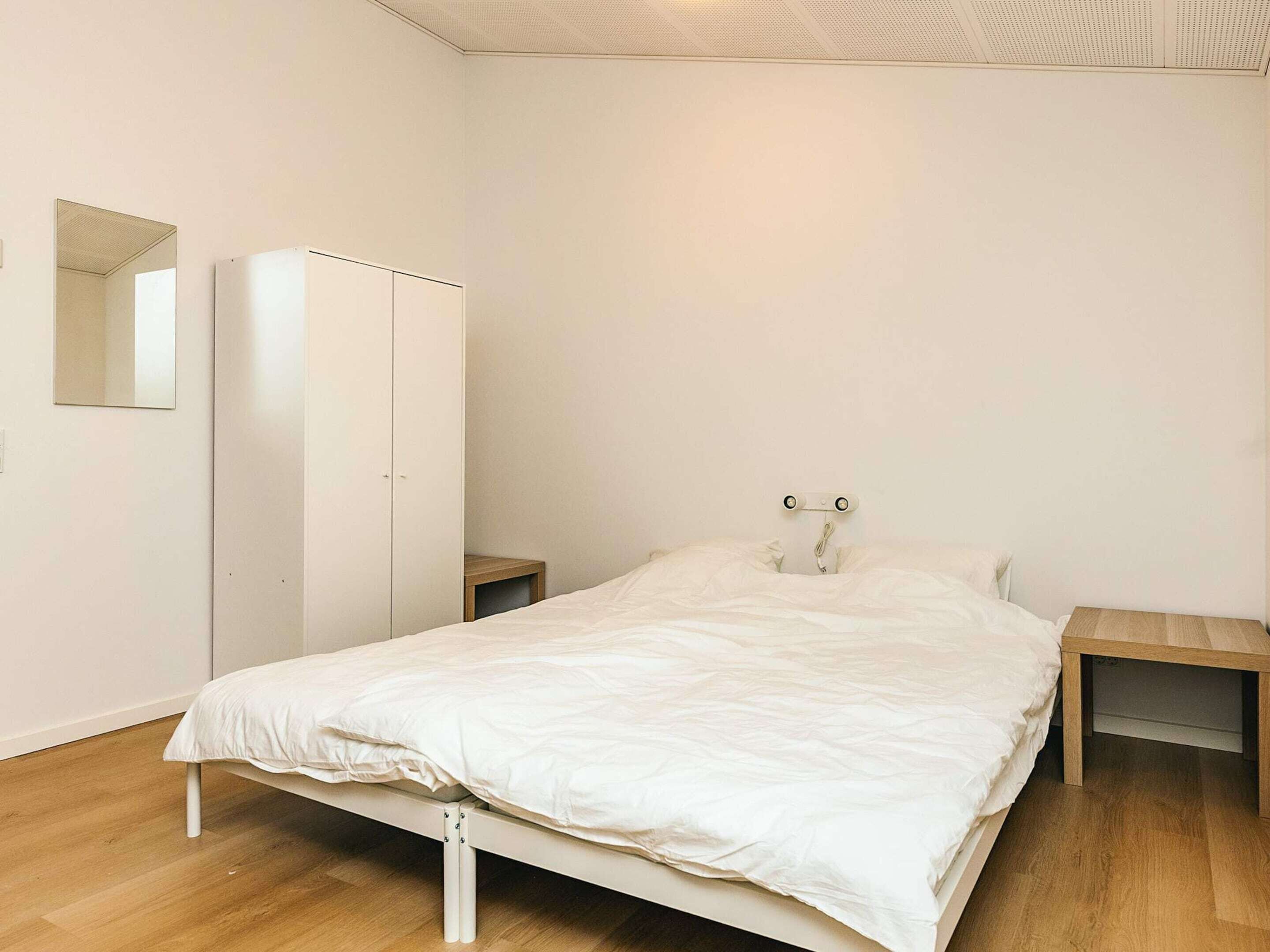 Une chambre à coucher comprenant un lit, une armoire, une table de chevet et un miroir.