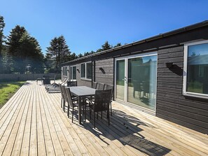 A wooden deck with outdoor furniture, a sliding glass door, and a view of the surrounding area. - 5 Star Holiday Home in Saltum (Saltum)