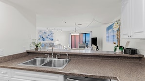 A modern kitchen with granite countertops, stainless steel sinks, and white cabinetry. - Gulf Coast Bliss Awaits - Reef Club 505 (Indian Rocks Beach)