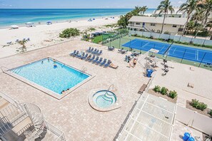 A pool area with a large pool, a smaller hot tub, and a tennis court. - Gulf Coast Bliss Awaits - Reef Club 505 (Indian Rocks Beach)