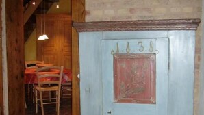 A room with a wooden door marked "1838" and a dining area with a table and chairs.