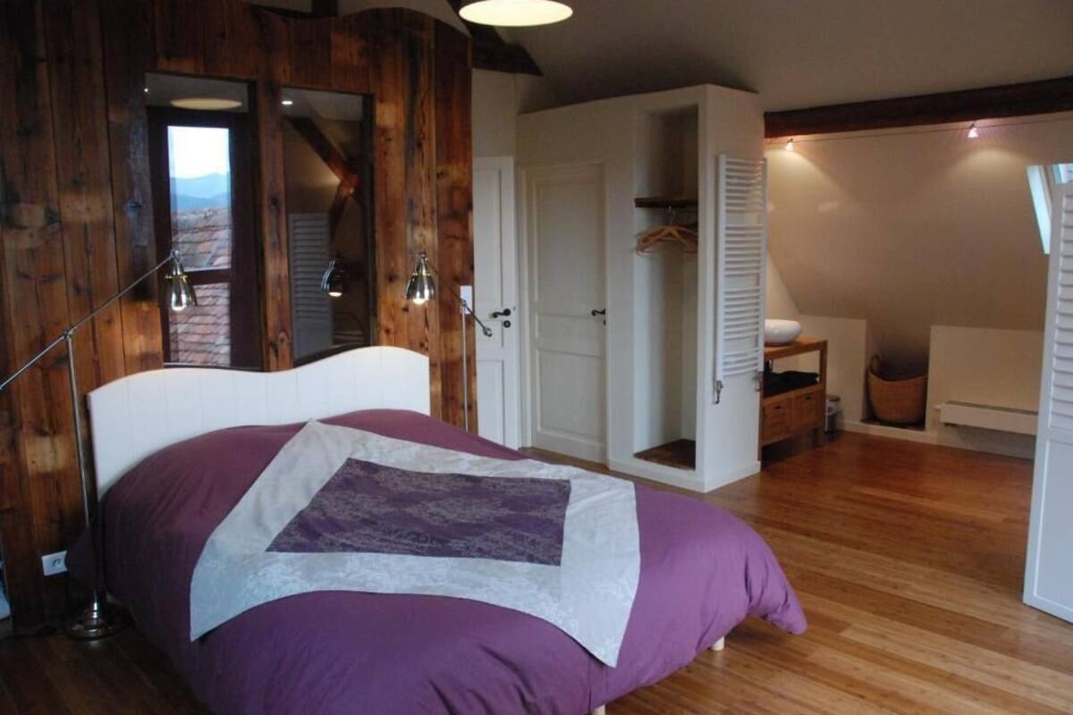 Une chambre à coucher avec un lit, des murs en bois, une porte blanche et un luminaire suspendu.