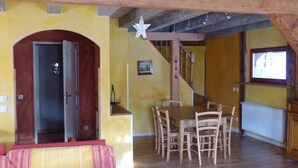 A dining area with a wooden table and chairs, a staircase, and a door leading to another room.