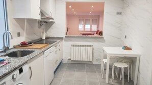 Una cucina compatta con lavatrice, lavello, piano di lavoro e zona pranzo con sgabelli.