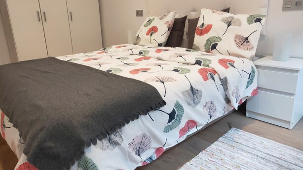Una camera da letto con un letto, comodini, un armadio e un tappeto decorato.