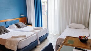 A hotel room with two beds, a small table with a bowl of snacks, a remote control, and a green placemat. - Hotel La Costiera (Giugliano in Campania)