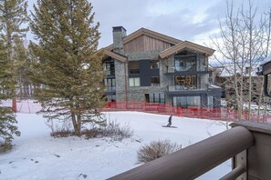 Een modern meerlaags huis met grote ramen en een stenen gevel, omgeven door sneeuw en bomen.