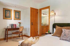 Une chambre d’hôtel comprenant un lit, un bureau avec une chaise, une armoire, un miroir et une lampe.