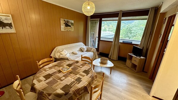 Ein gemütliches Zimmer mit einer holzgetäfelten Wand, einem Bett mit einer Quilttdecke, einem kleinen Tisch mit einem Korb und einem Fernseher auf einem Holzboden.