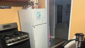 A kitchen with a stove, refrigerator, and dining table. - Soothing 2-bedroom house with AC in charming 3 mins from Dearborn Hts (Inkster)