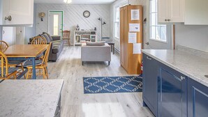 A modern kitchen with a marble countertop, wooden cabinets, and a blue rug. - Whimsical Waterside Cottage (Sharbot Lake)