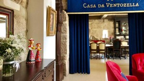 A room with a stone wall, a framed portrait, a decorative figurine, and a blue banner reading "Casa da VentoZella". - Family Retreat at a Country House (Penafiel)