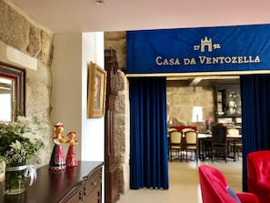A room with a stone wall, a framed portrait, a decorative figurine, and a blue banner reading "Casa da VentoZella". - Family Retreat at a Country House (Penafiel)