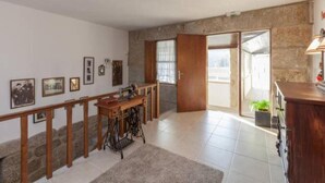 A spacious room with a large wooden desk, a sewing machine, and a staircase leading to a balcony. - Family Retreat at a Country House (Penafiel)
