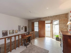 A spacious room with a large wooden desk, a sewing machine, and a staircase leading to a balcony. - Family Retreat at a Country House (Penafiel)