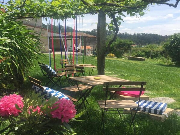 A garden with wooden furniture, a tree, and a building in the background. - Family Retreat at a Country House (Penafiel)