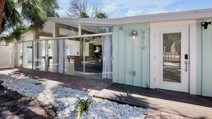 Een modern huis met grote glazen deuren, een houten terras en het nummer 4510 op de deur.