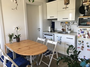 Una cocina funcional con armarios blancos, una mesa de comedor de madera y sillas.