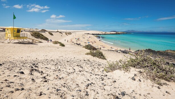 A beach with a lifeguard tower, sandy dunes, and clear turquoise waters. - Home2Book Casa María Rustic Escape in Villaverde (Villaverde)