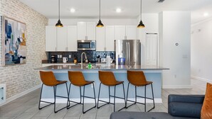 Una cucina moderna con isola centrale, sgabelli da bar e luci a sospensione.