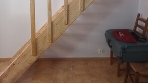 A staircase with wooden beams, a chair, and a red object on the floor.