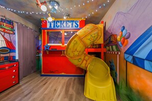 A play area with a ticket booth, a yellow slide, and a mural of a circus scene. - Sleeps 22•Pvt pool•Theater•Game room (Kissimmee)