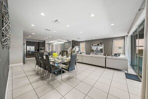 Cocina moderna con comedor, que cuenta con una isla central, luces empotradas en el techo y vistas de la ciudad a través de amplias ventanas.