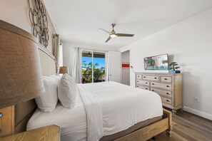 Un dormitorio con cama, cómoda, ventilador de techo y puerta que da a un balcón.