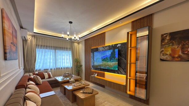 A modern living room with a large flat-screen TV, a sofa, a coffee table, and a decorative plant. - Sunny & Luxury Retreat Casablanca (Casablanca)