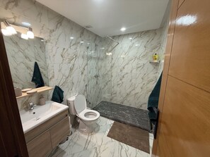 Une salle de bain moderne avec un mur en marbre, une douche, des toilettes et un lavabo.