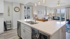 Una cocina moderna con una isla grande, lavavajillas integrado e iluminación colgante.