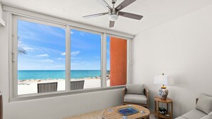 A room with a large window, a ceiling fan, a round table, a sofa, and a lamp. - Your Gulf-Front Getaway Awaits (Siesta Key)