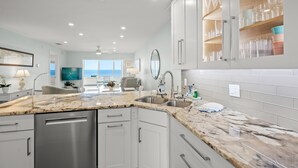 A modern kitchen with granite countertops, stainless steel appliances, and white cabinetry. - Gulf-Front Serenity at Fisherman’s Cove (Siesta Key)