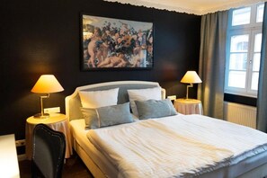 A hotel room with a large bed, two bedside tables with lamps, a black-framed picture on the wall, and a window with curtains. - Rein Klassik Hotel (Bad Pyrmont)