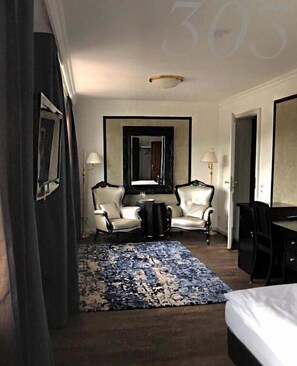 A hotel room with a bed, two armchairs, a desk, a mirror, and a large rug. - Rein Klassik Hotel (Bad Pyrmont)