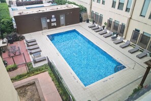 En rektangulär swimmingpool med solstolar och ett kaklat poolområde.
