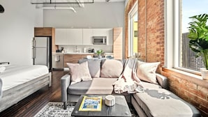 Een modern appartement met een zithoek, kitchenette en een groot raam met uitzicht.
