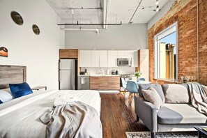 En modern lägenhet med en stor säng, en soffa, ett kök och en matplats.