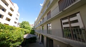 Ein mehrstöckiges Wohngebäude mit Balkonen, einer überdachten Außenbereich-Sitzgelegenheit und einem gepflegten Garten.