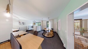 Ein modernes Hotelzimmer mit Essbereich, einer Couch und Blick ins Freie.