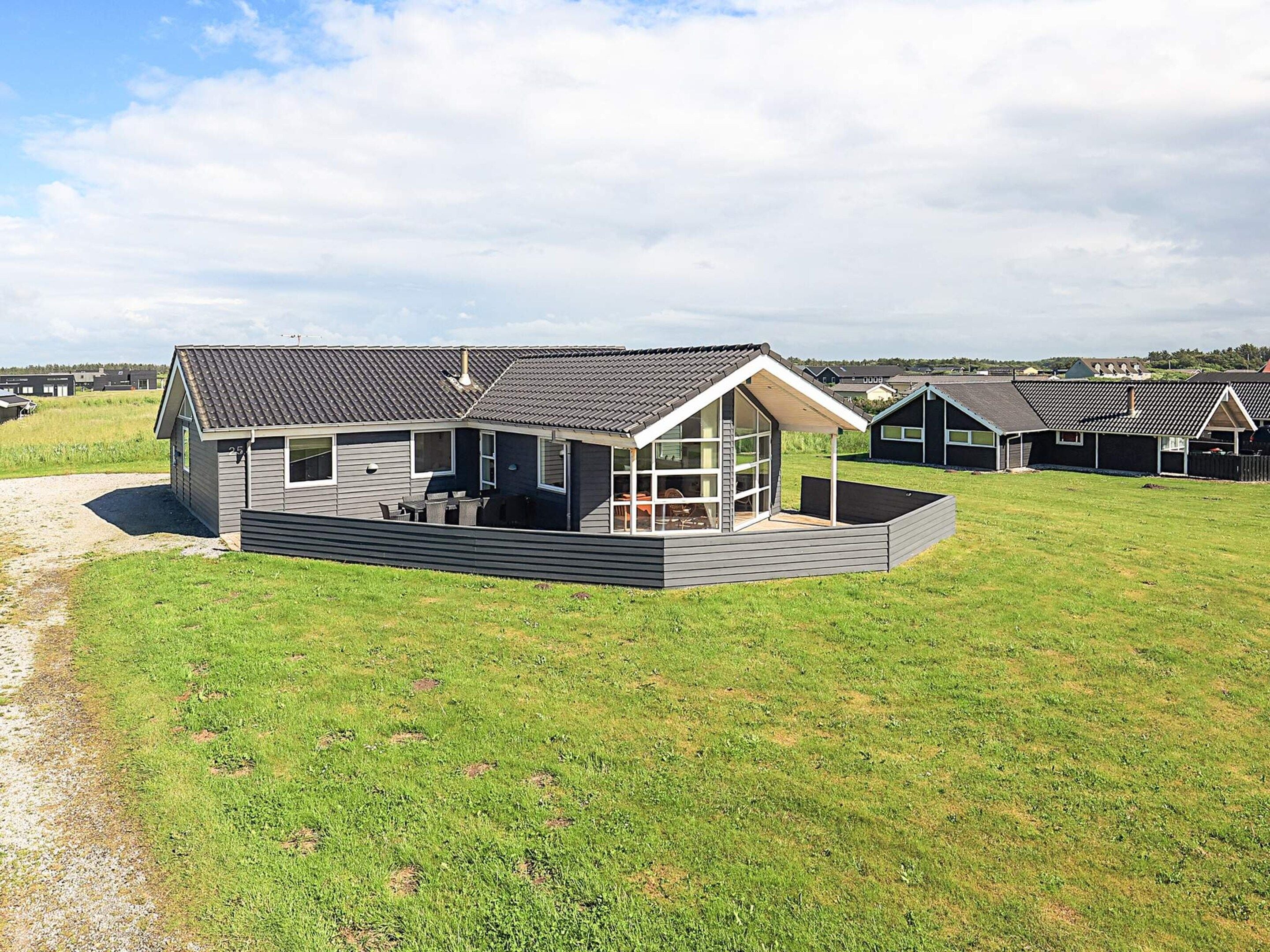 A modern house with a large deck, a covered patio, and a view of the surrounding area.