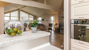 A spacious kitchen with a granite countertop, a refrigerator, and a dining area with wicker furniture. - 5 Star Holiday Home in Lokken (Lokken)