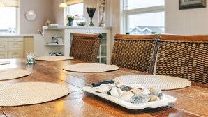 A dining area with a wooden table, woven placemats, and a tray of seashells. - 5 Star Holiday Home in Lokken (Lokken)