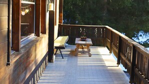 A wooden deck with a railing, a table, and a bench.