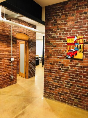 A hallway with brick walls and a polished floor, leading to a door.