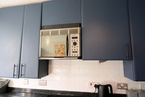 A kitchen with blue cabinets, a microwave, and a kettle. - Parking|Sleeps 8| 3 Bedroom House| City Centre (Edinburgh)