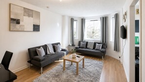 Un salon moderne avec deux canapés, une table basse et un tableau accroché au mur.